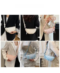 Detailaufnahmen der Schmetterlingsstickerei auf Knödeltaschen in Weiß, Rosa und Blau