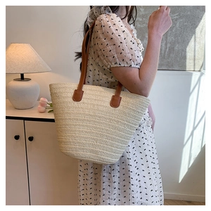 Detail of hand-woven straw tote with premium brown leather handles for summer beach use