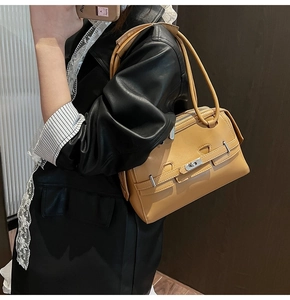 Detailed view of light brown leather underarm bag with silver twist lock and strap