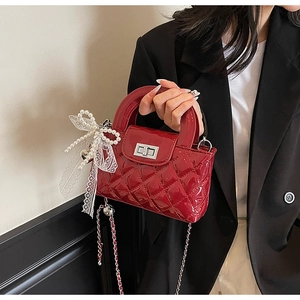 Detail of red quilted leather bag with silver twist lock and pearl bow charm