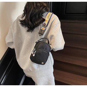 Vue arrière d'un sac bandoulière noir en nylon avec une large sangle à motifs