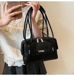 Close-up of black leather tote bag with silver buckle and decorative belt detail