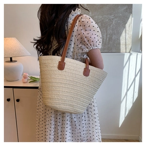 Beige straw tote bag with brown leather handles styled with a floral summer dress