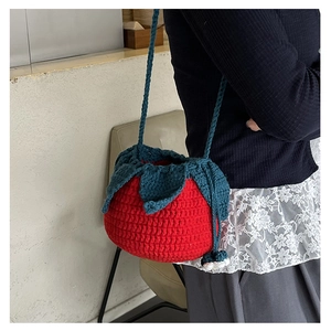 Macro shot of a handmade crochet strawberry shoulder bag with green leaf lid detail