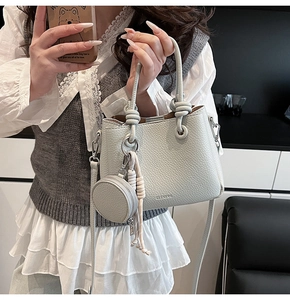 Detail of grey lychee leather bucket bag with knot handle and round coin purse charm