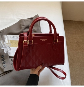 Close-up of red quilted leather tote with gold hardware and logo on a chic business suit