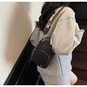 Détail de la bandoulière jacquard et du logo argenté sur un sac en nylon noir
