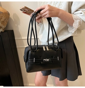 Detail of minimalist black leather underarm bag with silver twist lock and dual zippers