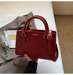 Detail of burgundy leather tote with diamond quilting, gold hardware and fashion logo