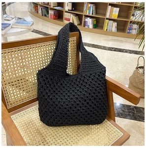 Detailed close-up of a black woven mesh beach bag on a vintage wooden chair