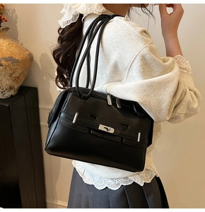 Detail of minimalist black glossy leather underarm bag with silver metallic buckle detail
