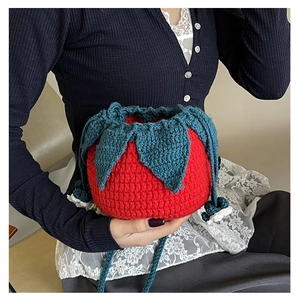 Close-up of handmade knit tomato drawstring bag with red wool texture and blue leaf detail