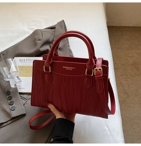 Close-up of deep red tote bag with wave-embossed texture and golden hardware details