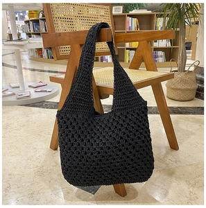 Close-up of black crochet woven shoulder bag with mesh pattern on a wooden chair