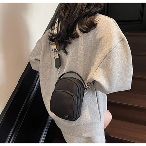Détail du sac bandoulière en nylon noir avec sangle jacquard florale et double zip