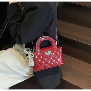 Detail of red quilted patent leather handbag with silver chain and lace bow charm
