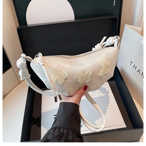 Nahaufnahme der weißen Spitzen-Schultertasche mit 3D-Schmetterlingen in einer Geschenkbox