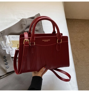 Detail of red leather bridal tote with wavy texture, gold hardware and shoulder strap