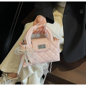 Detail of pink patent leather handbag with quilted patterns and lace pearl charm decor