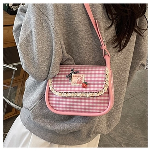 Detail of pink plaid canvas bag with lace trim, bow, and strawberry charm decoration