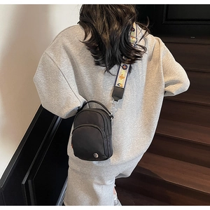 Détail du sac bandoulière en nylon noir avec une large sangle en jacquard tissé