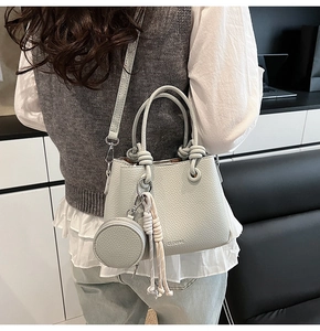 Close-up of light grey lychee leather bucket bag with coin purse and knotted tassel