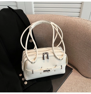Detail view of beige leather shoulder bag with triple zippers and silver hardware accents