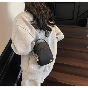 Vue arrière d'un sac bandoulière noir en nylon avec large sangle sur un modèle
