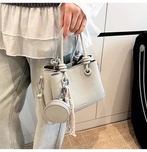 Detail of light gray lychee grain leather bucket bag with CLEARER logo and silver hardware