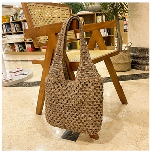 Detail of hollow-out weave texture and dark fabric lining on a brown straw tote bag