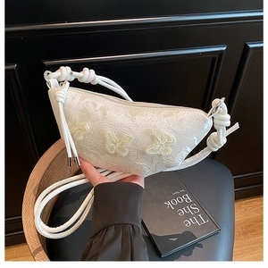 Detaillierte Stickerei und 3D-Schmetterlingsapplikationen auf weißer Tasche