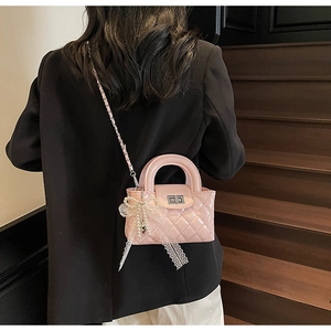 Detail of pink quilted handbag with lace pearl bow charm and metal chain strap