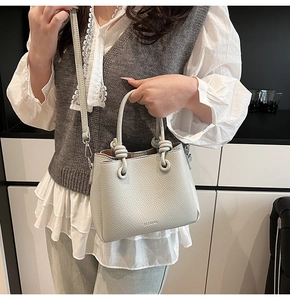 Close-up of light gray bucket bag showing lychee leather texture and knot handle