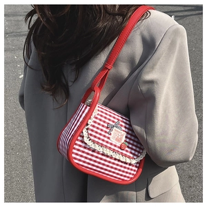 Close-up of red plaid canvas bag with lace trim, strawberry charm and bow detail