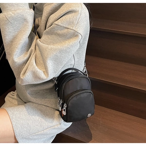 Détail d'un sac à bandoulière noir en nylon avec fermetures éclair sur un mannequin