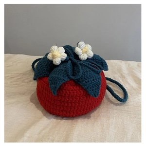 Detail of handmade crochet strawberry knit shoulder bag with green leaves and white flowers