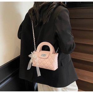 Detail view of pink quilted patent leather crossbody bag with lace bow and pearl charm