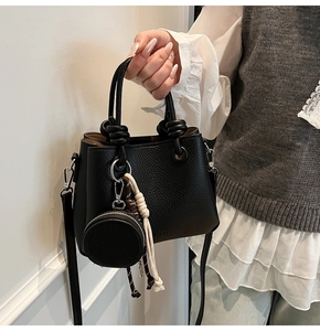 Close-up of black lychee grain bucket bag with knot handle and detachable strap