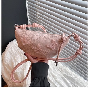 Detail der rosa Schmetterlingsstickerei aus Spitze und kreativ geknoteter Leder-Schultergurt