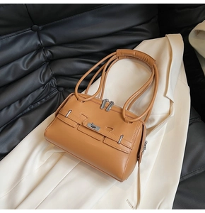 Close-up of caramel leather shoulder bag with metal lock detail and silver zipper