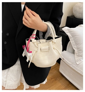 Close-up of white crocodile pattern bucket bag with silk scarf handle and horse charm