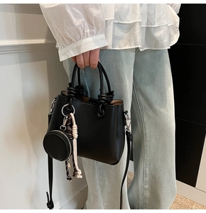Close-up of black lychee grain leather bucket bag with knot detail and mini coin purse