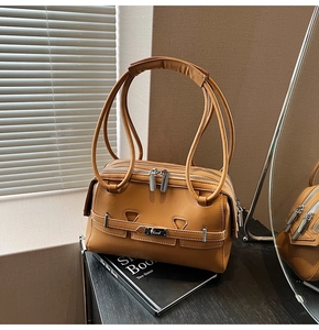 Detail of caramel underarm bag featuring three silver zippers and slender shoulder straps