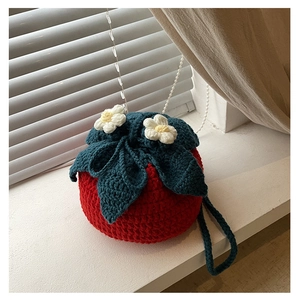 Detailed knit texture of handmade strawberry crochet bag with white daisy flower accents