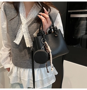 Detail of black lychee grain bucket bag featuring knot handle and mini charm