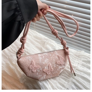 Detailaufnahme der rosa Spitzen-Halbmondtasche mit 3D-Schmetterlingsstickerei und Knotengurt