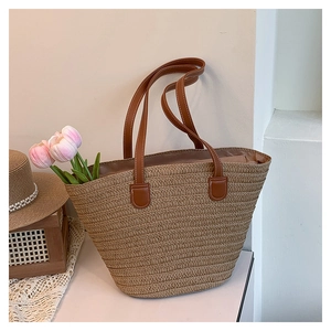 Detail of woven straw tote bag with brown leather handles and decorative tulips