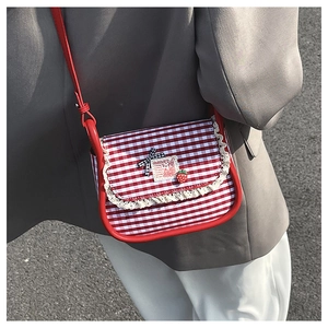 On-body shot of a small red and white plaid crossbody bag with lace trim and bow detail