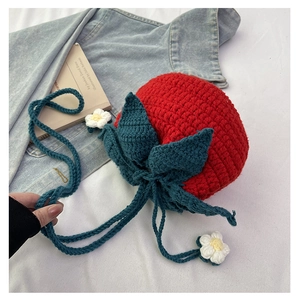 Detailed knit texture of handmade strawberry crochet bag with white floral accents