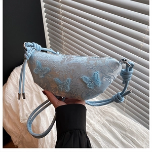 Detailansicht der hellblauen Spitzen-Halbmondtasche mit 3D-Schmetterlingen und Knoten